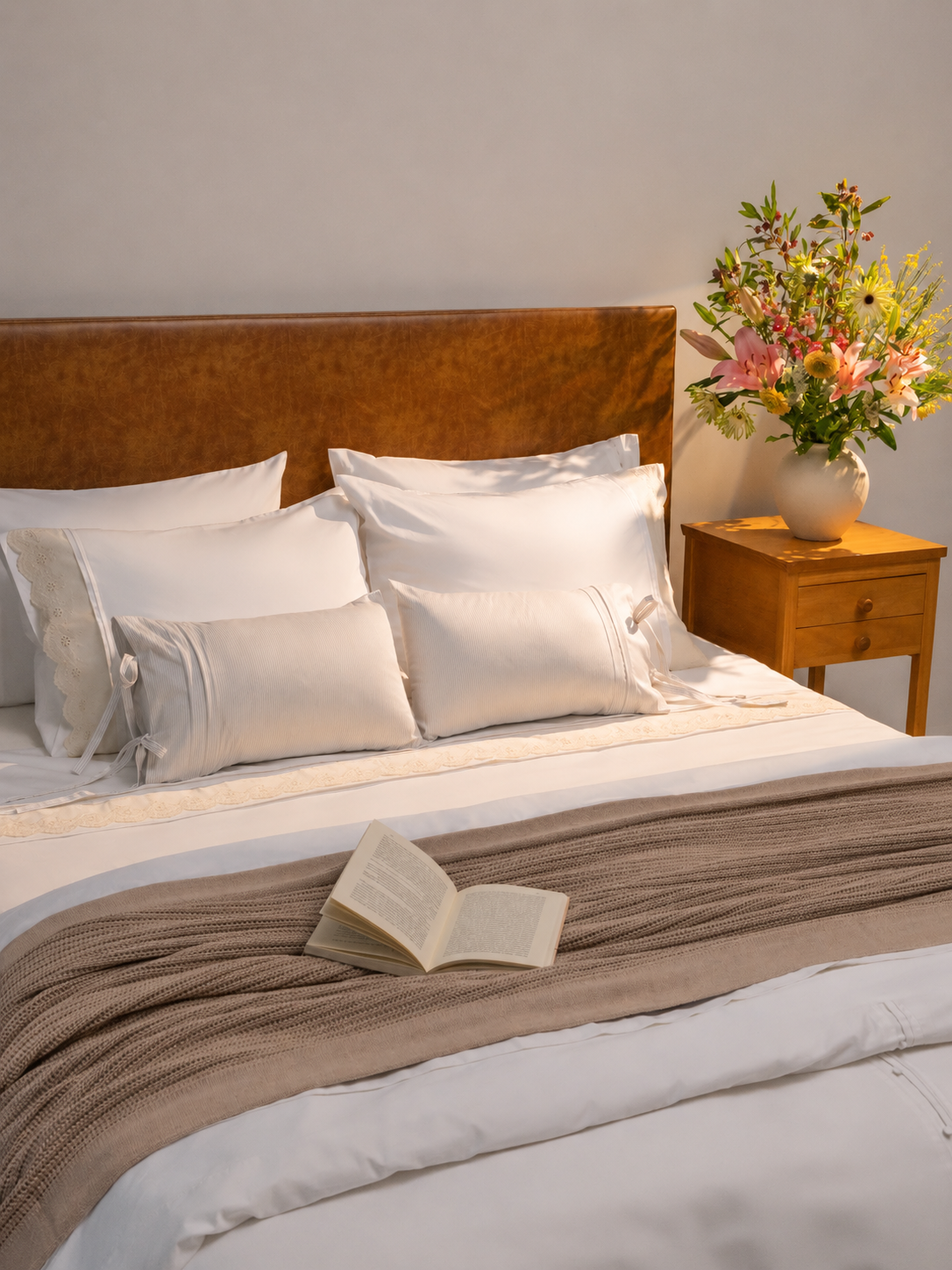 Cama arrumada com tecidos claros, almofadas e composição aconchegante